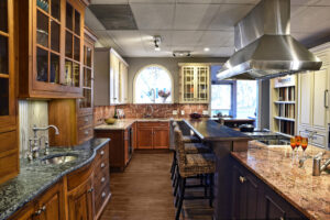 Modern kitchen with wood cabinets, granite countertops, island seating, and stainless steel range hood.
