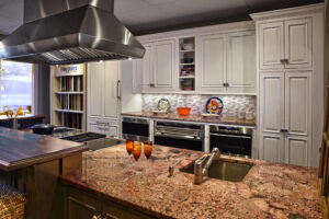 Modern kitchen with granite island, white cabinets, stainless appliances, and two drinks on the counter.